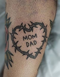 a tattoo on the leg of a man with barbed wire around it that says, mom dad