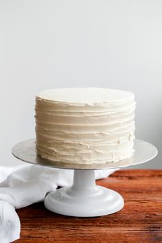 a white frosted cake sitting on top of a wooden table