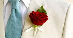 a man wearing a suit and tie with a red rose pinned to his lapel