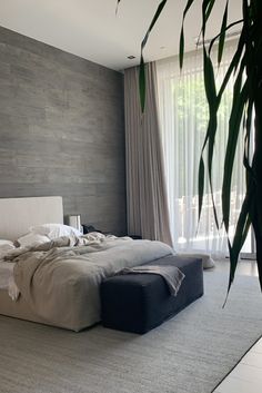 a large bed sitting in the middle of a bedroom next to a tall green plant