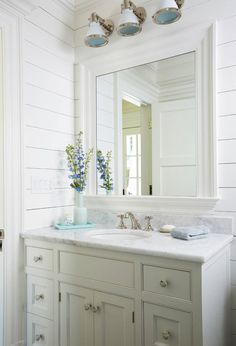 a white bathroom with two sinks and a large mirror above the sink is decorated with blue flowers