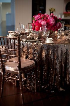 the table is set with silver and pink flowers