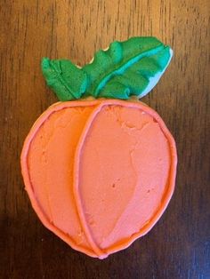 an orange shaped cake sitting on top of a wooden table next to a green leaf