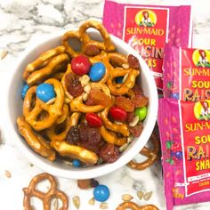 two bags of sun maid raisins next to a bowl of pretzels