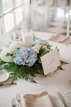 a centerpiece with flowers and greenery on a table