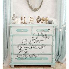 a dresser with flowers painted on it and a mirror above the drawers in front of it