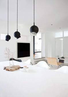 a bedroom with white walls and black lamps hanging from the ceiling, along with modern furniture