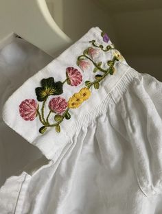 a close up of a white shirt with flowers embroidered on the front and back side