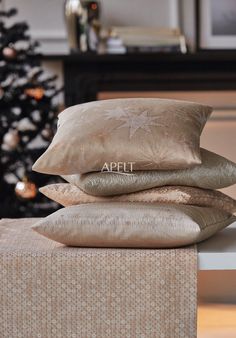 four pillows stacked on top of each other in front of a christmas tree