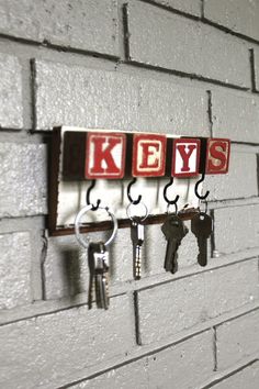 keys are hanging on the key holder in front of a brick wall that says keys