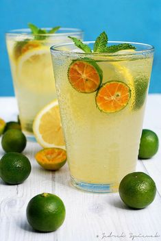 two glasses filled with lemonade and limes