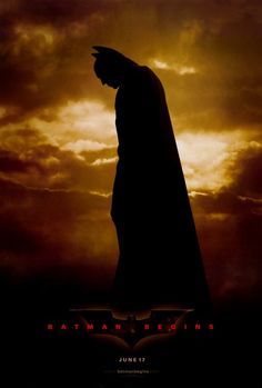 the dark knight rises movie poster with batman silhouetted against cloudy sky and sunbeams