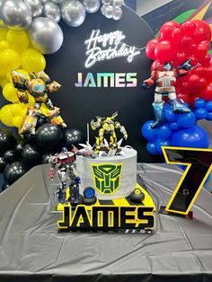 a birthday cake with the name james 7 in front of some balloons and other decorations