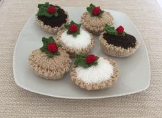 four crocheted cupcakes on a white plate with red flowers and green leaves