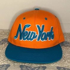 New York Snapback Hat From City Hunter Usa New Without Tags Bright Orange With Teal Lettering Size: Osfm Snap Back Color: Orange And Teal Condition: New Without Tags **Questions? Just Ask!** Please See Photos For Details And Personal Judgment On Condition Bin 1 3.4oz New York Snapback Hat Bright Style Staple Wardrobe Basics Goals Versatile Value Dandirandi Vintage Orange Snapback Hat, Orange Snapback Hat For The Beach, Orange Snapback Hat For Beach, Orange Baseball Cap For Beach, Retro Orange Baseball Cap With Curved Brim, Casual Orange Snapback Hat With Flat Brim, Vintage Orange Adjustable Hat, Orange Snapback Hats For Streetwear, Orange Casual Snapback Hat With Flat Bill