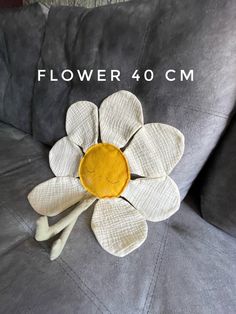 a white flower sitting on top of a gray couch with the words flower 40 cm above it