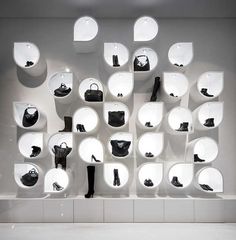 a display in a store filled with lots of white shelves and black shoes on top of each shelf