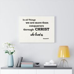 a white wall with a quote on it that says, in all things we are more than conquers through christ who loves us