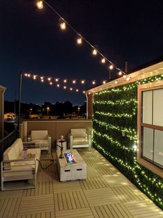 an outdoor living area with lights strung on the wall and wooden flooring, along with couches and chairs