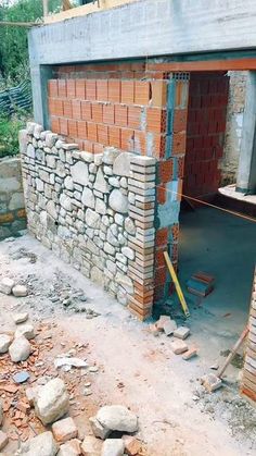 a building under construction with brick walls and bricks on the side, surrounded by rocks