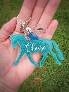 a hand holding a blue horse keychain with the word equise on it