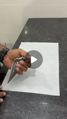 a person is cutting paper with scissors on a table in front of a white sheet of paper