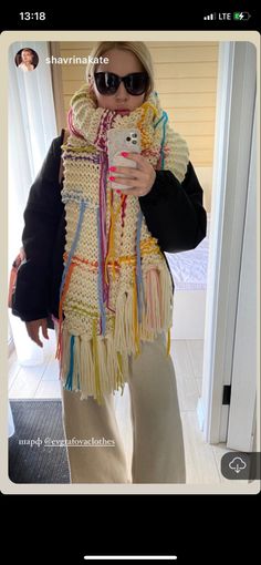 a woman taking a selfie with her cell phone wearing a crocheted scarf