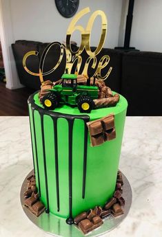 there is a green cake with gold lettering on it and a tractor in the middle