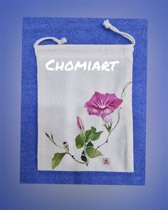 a towel hanging on a blue wall with a pink flower and the word chomiart written in white