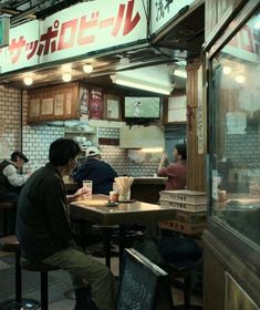 people sitting at tables in a restaurant with menus on the wall and signs above them