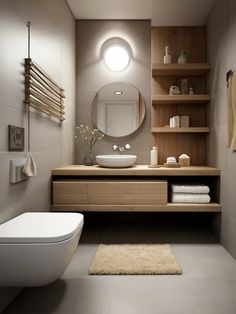 a white toilet sitting next to a bathroom sink under a round mirror on a wall