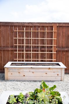 a wooden planter box sitting on top of a gravel ground