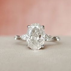 an oval cut diamond ring with three pear shaped diamonds on the band and side stones