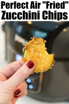 a woman holding up a piece of food in front of an air fryer