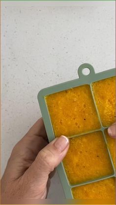 a person holding up a square container with food in it