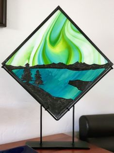 a stained glass art piece sitting on top of a wooden table