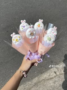 a hand holding a bunch of pink flowers with bunny ears on them and buttons in the middle