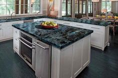 a large kitchen with an island in the middle and marble counter tops on both sides