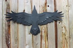 a metal bird is mounted to the side of a wooden fence with it's wings spread out