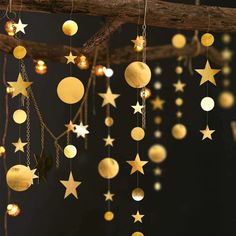 gold stars hanging from a tree branch with lights on them and some chains attached to the branches