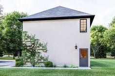 a small white house with a gray door and windows on the side of it, surrounded by green grass