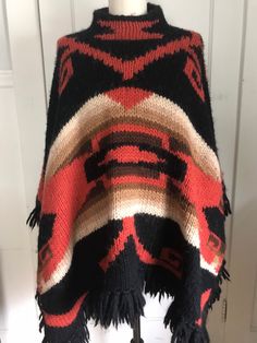 Vintage Ralph Lauren Hand knit Poncho Ralph Lauren Sweater Coat Iconic Indian Blanket pattern Shawl Cape Tribal Luxuriously warm and cozy hand knit Southwestern  Native American  Tribal pattern Thick chunky Wool Fringed  One size fits most 1  SP 29 LENTH SHOULDER DOWN BOTTOM FRINGE 25 SIDE NECK DOWN TO BOTTOM FRINGE HANGS ADDL 3-5 INCHES LONGER POINTS ON SIDE Vintage Ralph Lauren Sweater, Hand Knit Poncho, Poncho Coat Cape, Knit Poncho Sweater, Turtleneck Poncho, Indian Blankets, Knit Poncho, Ladies Poncho, Sweater Scarf