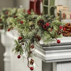 pine cones and red berries are on the mantle