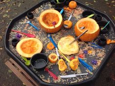 pumpkins and other halloween decorations are arranged in a tray on the ground with paintbrushes