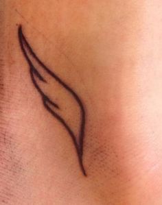 a small tattoo on the back of a woman's neck with an angel wing