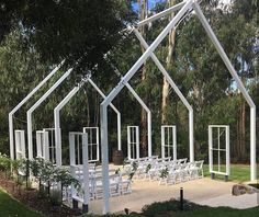 an outdoor wedding venue set up with white chairs and windows in the shape of a house