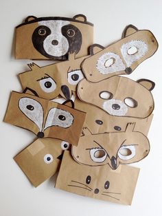 some brown paper bags with animal masks on top of each bag and one is cut out to look like a raccoon