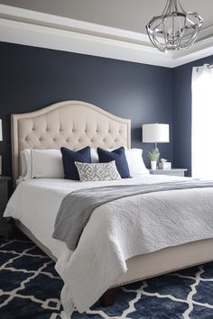 a bedroom with blue walls, white bedding and a chandelier hanging from the ceiling