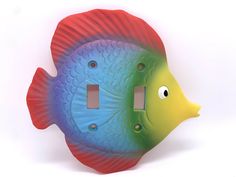 a multicolored fish light switch plate cover with two eyes on it's side