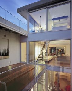 the inside of a modern house with glass walls and stairs leading up to the second floor